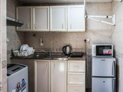 a kitchen with white cabinets and a sink and a refrigerator at Al Ferdous Hotel Apartment in Sharjah