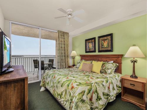 a bedroom with a bed and a television and a balcony at Lovers Key Resort 503 - Fort Myers in Fort Myers Beach