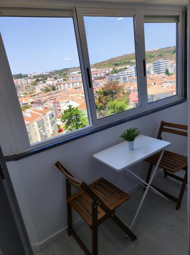 a table and two chairs in a room with windows at Vista Panorâmica Amadora in Amadora