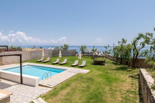 a backyard with a swimming pool and chairs and the ocean at Armonia Seaside Villas in Vasilikos