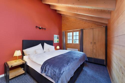 a bedroom with a large bed and a red wall at Chalet Eigersunna in Grindelwald