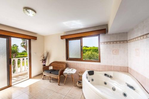 a bathroom with a tub and a chair and windows at Villa Polyxeni in Peyia