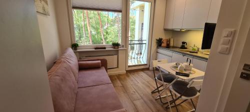 un soggiorno con divano e tavolo e una cucina di Apartament 100 Blue Mare a Łukęcin