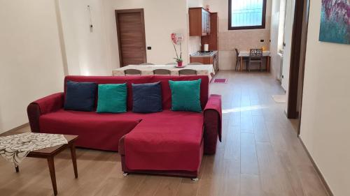 a living room with a red couch with blue and green pillows at Dasylirion Vacanze in Cursi