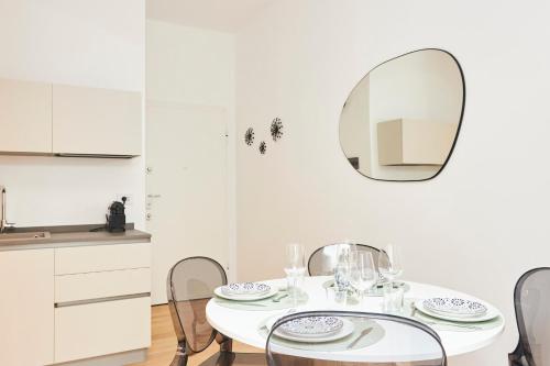 uma sala de jantar branca com uma mesa branca e um espelho em MILANO URBAN FLATS Modern apartments few minuts from Duomo em Milão