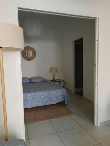 une chambre avec un lit dans une pièce blanche dans l'établissement Appartement T2 avec jardin privatif 3 étoiles, à Mèze