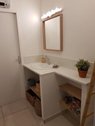 une salle de bain blanche avec un lavabo et un miroir dans l'établissement Appartement T2 avec jardin privatif 3 étoiles, à Mèze