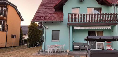 una casa azul con mesas y sillas en un patio en U Izy i Romana en Jarosławiec