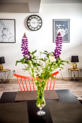 a vase with purple flowers sitting on a table at Apartamenty Dwupoziomowe Na Dwa Widoki z Jacuzzi & Sauna in Zakopane