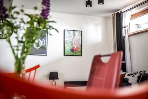 a living room with a red chair and a table at Apartamenty Dwupoziomowe Na Dwa Widoki z Jacuzzi & Sauna in Zakopane