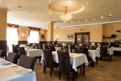 a restaurant with white tables and chairs and a chandelier at Grand Hotel Pylypets in Pilipets