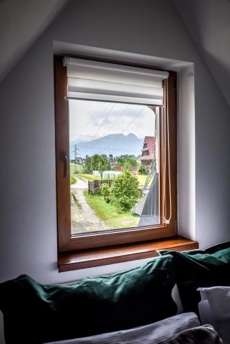 a window with a green couch looking out of it at Apartamenty Dwupoziomowe Na Dwa Widoki z Jacuzzi & Sauna in Zakopane