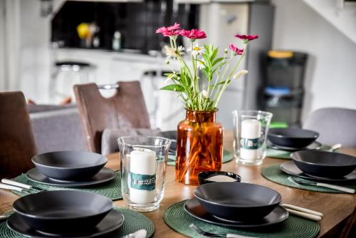 a wooden table with black plates and flowers in a vase at Apartamenty Dwupoziomowe Na Dwa Widoki z Jacuzzi & Sauna in Zakopane