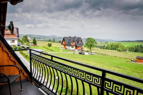 a balcony with a view of a field and houses at Apartamenty Dwupoziomowe Na Dwa Widoki z Jacuzzi & Sauna in Zakopane
