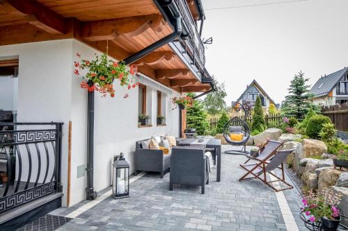 a patio with chairs and tables on a house at Apartamenty Dwupoziomowe Na Dwa Widoki z Jacuzzi & Sauna in Zakopane
