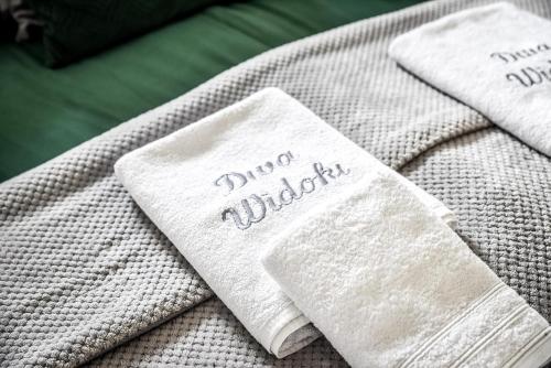 two white towels sitting on top of a bed at Apartamenty Dwupoziomowe Na Dwa Widoki z Jacuzzi & Sauna in Zakopane