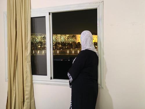 a woman looking out the window of a room at Gem Overlooking inn in Cairo