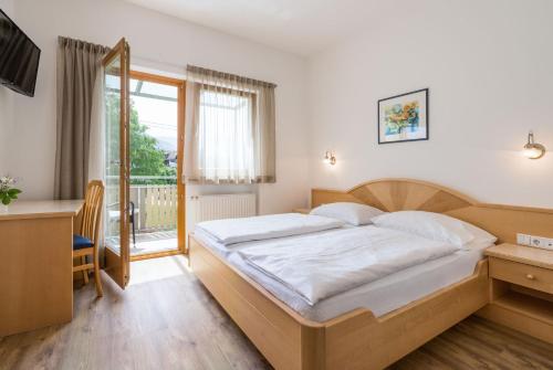 a bedroom with a bed and a desk and a window at Garni Schorneck in Brunico
