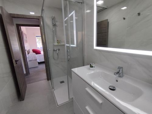 uma casa de banho branca com um lavatório e um chuveiro em Apartamento Pie de Playa, El Puntal-Villaviciosa em Villaviciosa