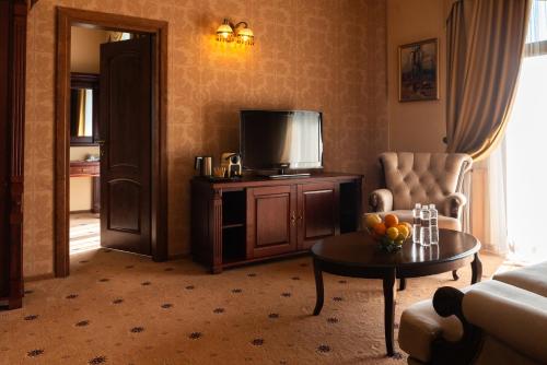 a living room with a couch and a tv and a table at Grand Hotel Pylypets in Pilipets