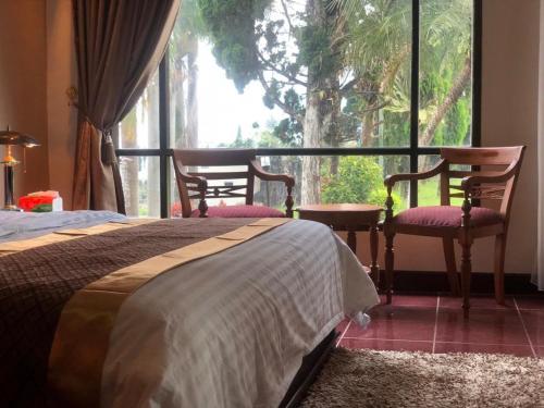 a bedroom with a bed and two chairs and a window at VILLA ISTANA 9 BEDROOMS in Puncak