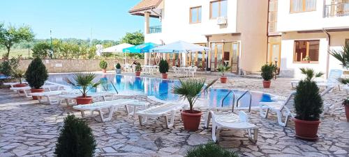 a hotel with a swimming pool with tables and chairs at Апартамент в Oasis beach Kamchia - Най-любимото синьо in Bliznatsi