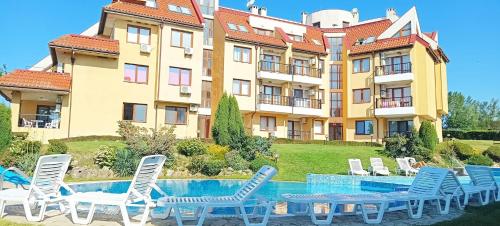 a hotel with chairs and a swimming pool in front of a building at Апартамент в Oasis Beach Kamchia -THE FAVOURITE BLUE in Bliznatsi