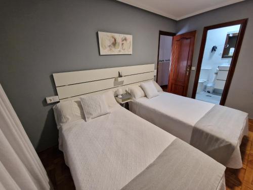 a bedroom with two beds and a mirror at Hostal Fidalgo in Oviedo