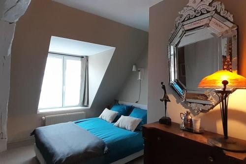 1 dormitorio con cama azul y espejo en Plage et port à 2 min - Appartement ensoleillé, en Dieppe