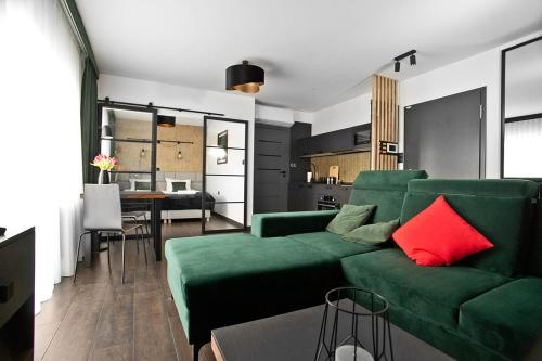 a living room with a green couch and red pillows at Exclusive Apartments with Private Parking and a Gym in Kraków