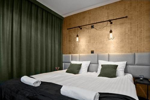 a bedroom with a large bed with green curtains at Exclusive Apartments with Private Parking and a Gym in Kraków