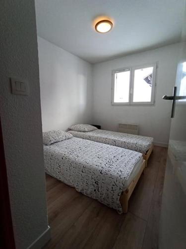 - 2 lits dans une petite chambre avec fenêtre dans l'établissement Appartement 1 chambre, résidence Les Chalets, à Puy-Saint-Vincent