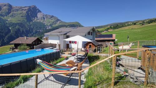 a house with a swimming pool and a mountain at Gasthaus Alpina in Tschappina