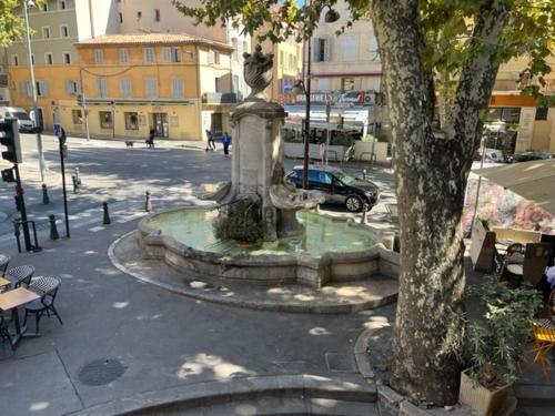 a fountain in the middle of a city with a tree at BLUE FOUNTAIN Luxueux Studio Aix Centre Historique -WIFI-SMART TV- in Aix-en-Provence