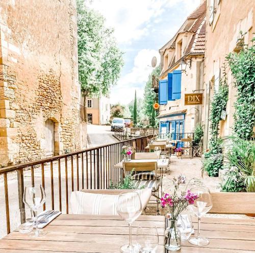 drewniany stół z krzesłami i kwiatami na balkonie w obiekcie DIX Restaurant & Chambres d'hotes w mieście Saint-Alvère