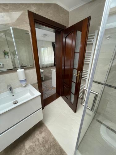 ein Bad mit einem Waschbecken, einer Dusche und einem Spiegel in der Unterkunft Pensiunea AlexOlar New One in Arada
