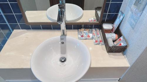 - un lavabo blanc dans une salle de bains avec deux miroirs dans l'établissement APEC Mũi Né - Hòn Rơm Phan Thiết, à Ấp Long Sơn