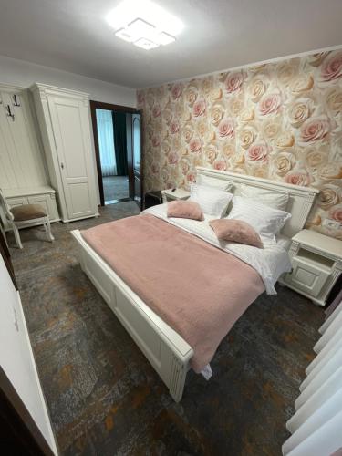 a bedroom with a large bed with pink sheets and pillows at Pensiunea AlexOlar New One in Horea
