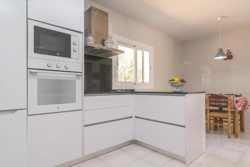 a kitchen with white cabinets and a microwave at Casa Aina in Sa Ràpita