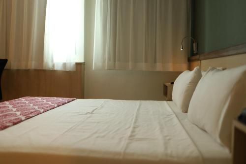 a bedroom with a large white bed with a window at Comfort Hotel Campos dos Goytacazes in Campos dos Goytacazes