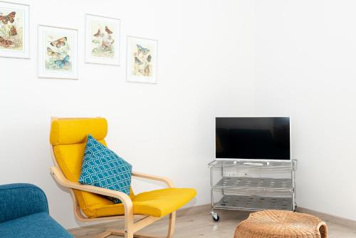 a living room with a yellow chair and a tv at Mamo's Belvedere by Holiday Solutions in Faggeto Lario 