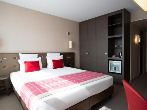 a bedroom with a large bed with red pillows at Mercure Clermont Ferrand centre Jaude in Clermont-Ferrand