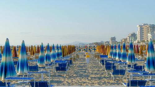 a row of chairs and umbrellas on a beach at Margherita 8 Apartments in Rimini