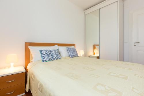 a white bedroom with a large bed with blue pillows at Villa Mare Crikvenica in Crikvenica