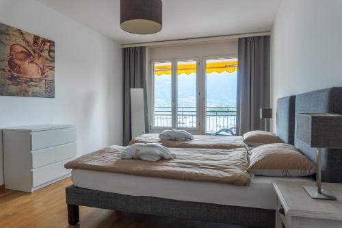1 Schlafzimmer mit 2 Betten und einem großen Fenster in der Unterkunft Tertianum Residenza Hotel & Ristorante Al Parco in Locarno