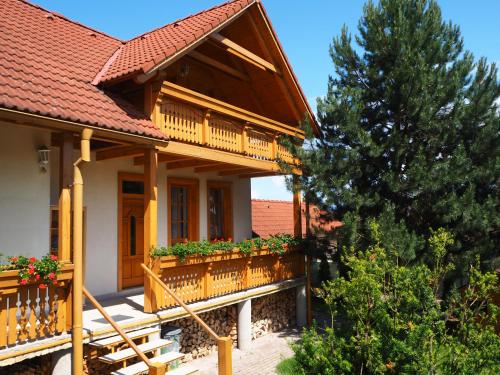 a house with a wooden balcony and a tree at Privat Alenka in Liptovský Mikuláš