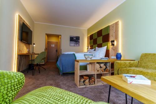 クアオルト・オーバーヴィーゼンタールにあるRathaushotels Oberwiesenthal All Inclusiveのベッド、テーブル、椅子が備わるホテルルームです。