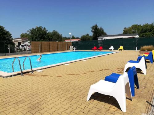 - une piscine avec des chaises bleues et blanches dans l'établissement Maison de type chalet piscine collective hume, à Gujan-Mestras