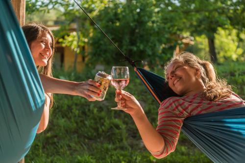 dwie kobiety trzymające kieliszki wina w rękach w obiekcie Szellős Rét Camping w mieście Bálványos