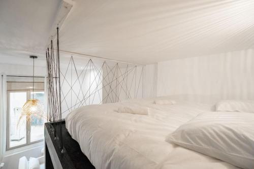 a white bedroom with a large bed and a window at  Le Bohème superbe Loft fonctionnel et central in Saint-Étienne